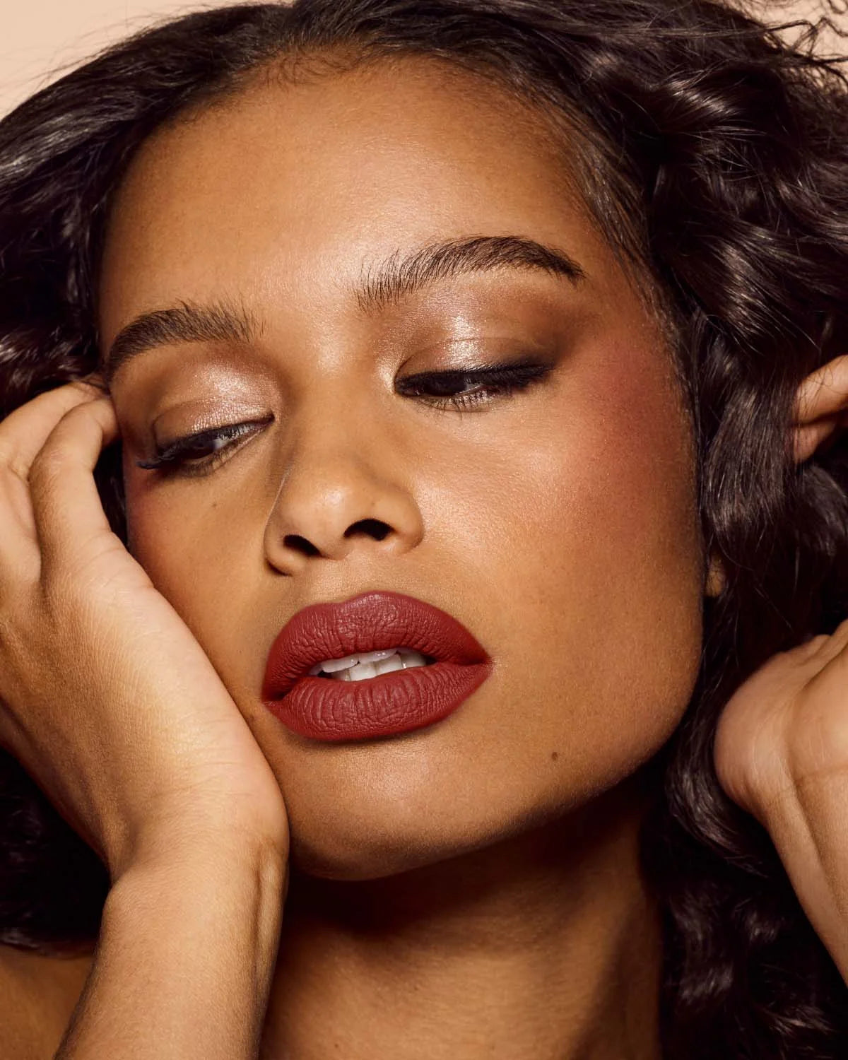 Close-up of a woman with red lipstick and hands on her face